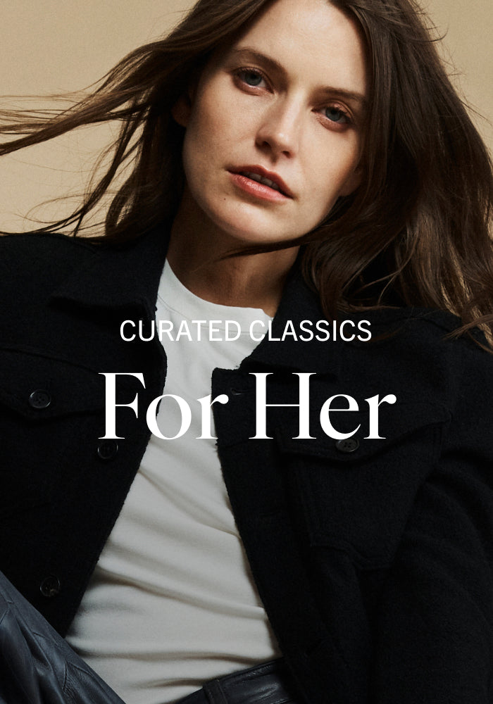 Woman wearing a black coat with text 'Curated Classics For Her' on a beige background