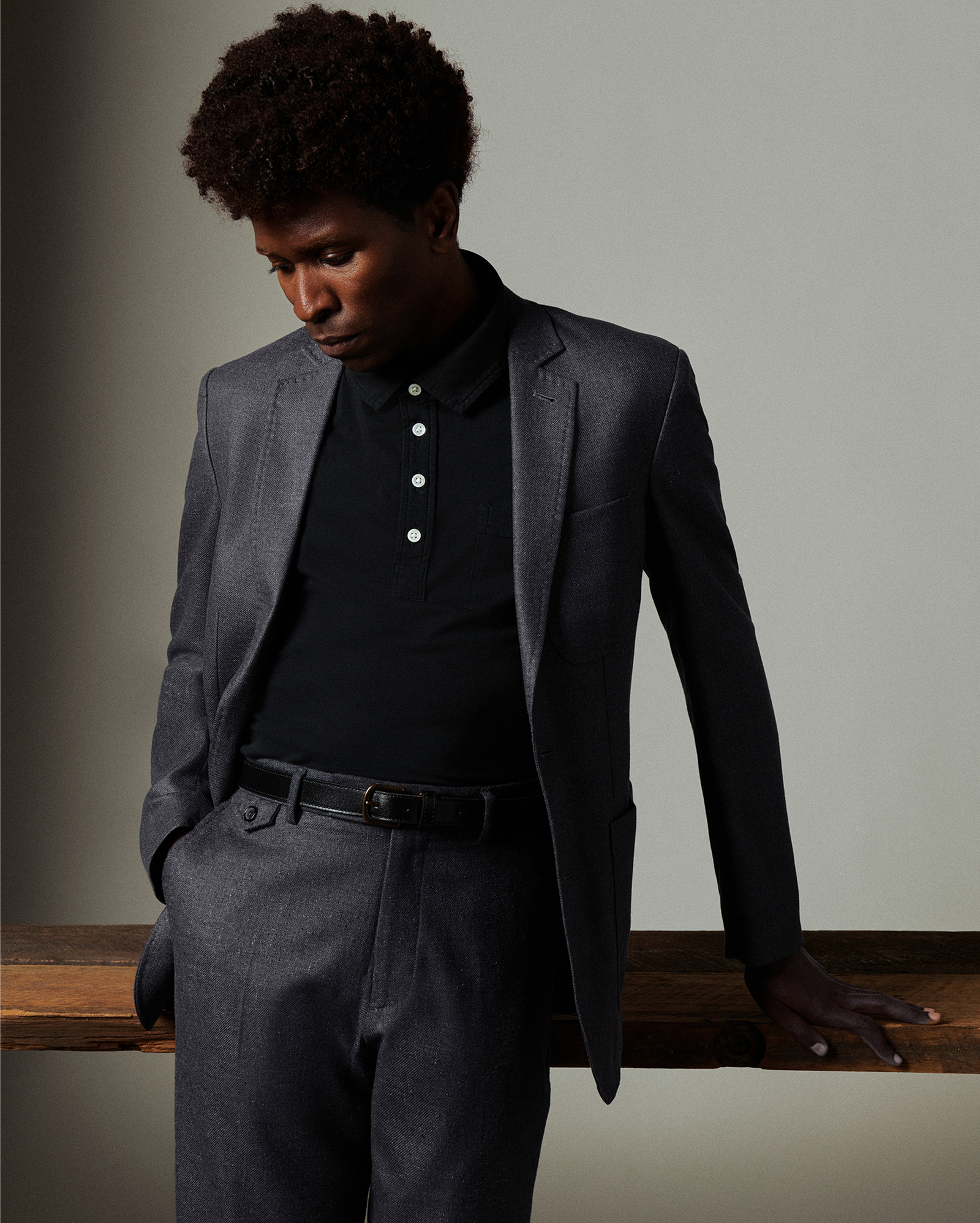 Man wearing a gray blazer over a black shirt with a plain background
