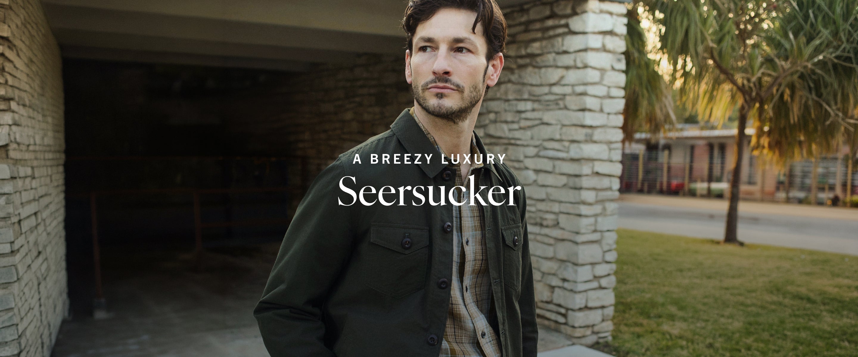Man standing outdoors with 'Seersucker' branding and 'A Breezy Luxury' text.