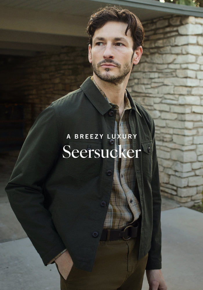Man wearing a dark jacket with 'Seersucker' branding in an outdoor setting.