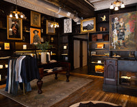 Vintage-style clothing store with wooden interior, hanging clothes, and framed artwork.
