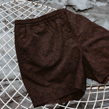 Brown patterned fabric on a wire mesh surface with a stone wall background
