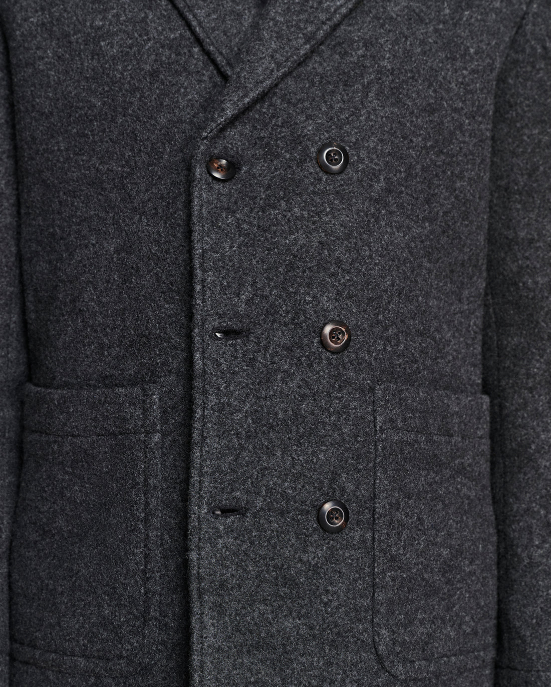 Close-up of a dark charcoal gray wool-blend double-breasted coat with dark buttons and front flap pockets.