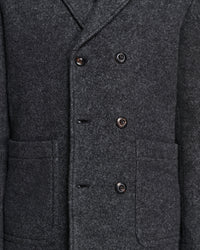 Close-up of a dark charcoal gray wool-blend double-breasted coat with dark buttons and front flap pockets.