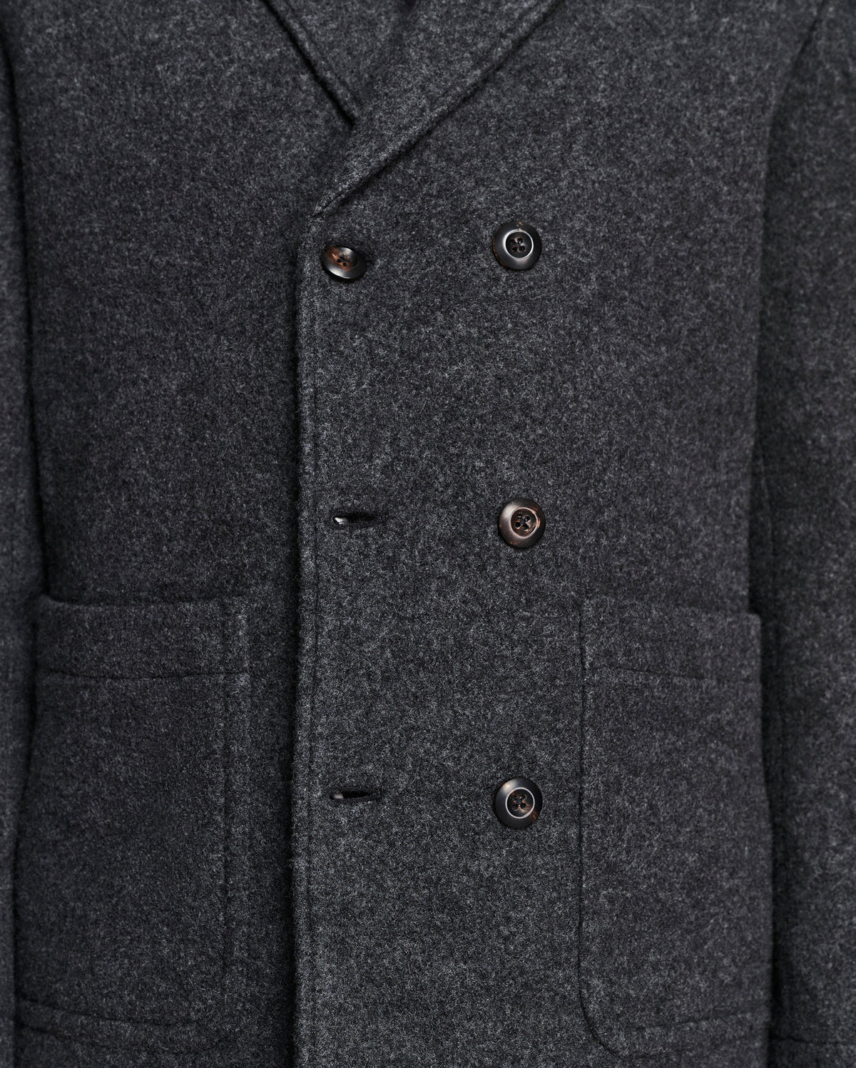 Close-up of a dark charcoal gray wool-blend double-breasted coat with dark buttons and front flap pockets.