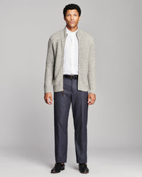 A man modeling a light gray textured knit cardigan over a white collared shirt, paired with dark gray trousers and black dress shoes, against a solid light gray studio background.