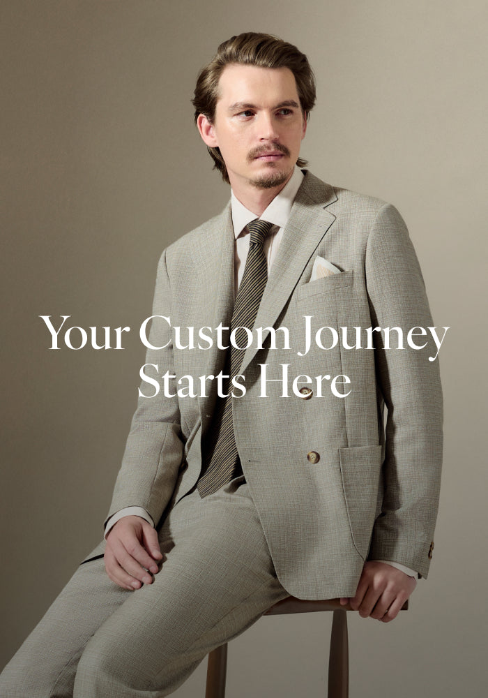 Man in a gray suit sitting on a stool with text 'Your Custom Journey Starts Here' on a plain background