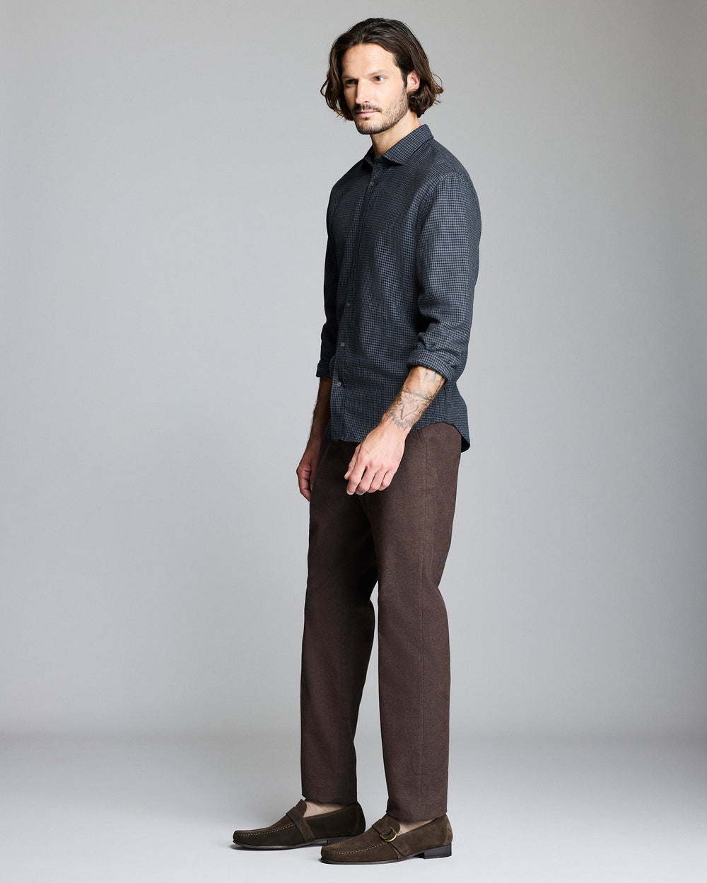 Man wearing a dark shirt and brown pants on a gray background