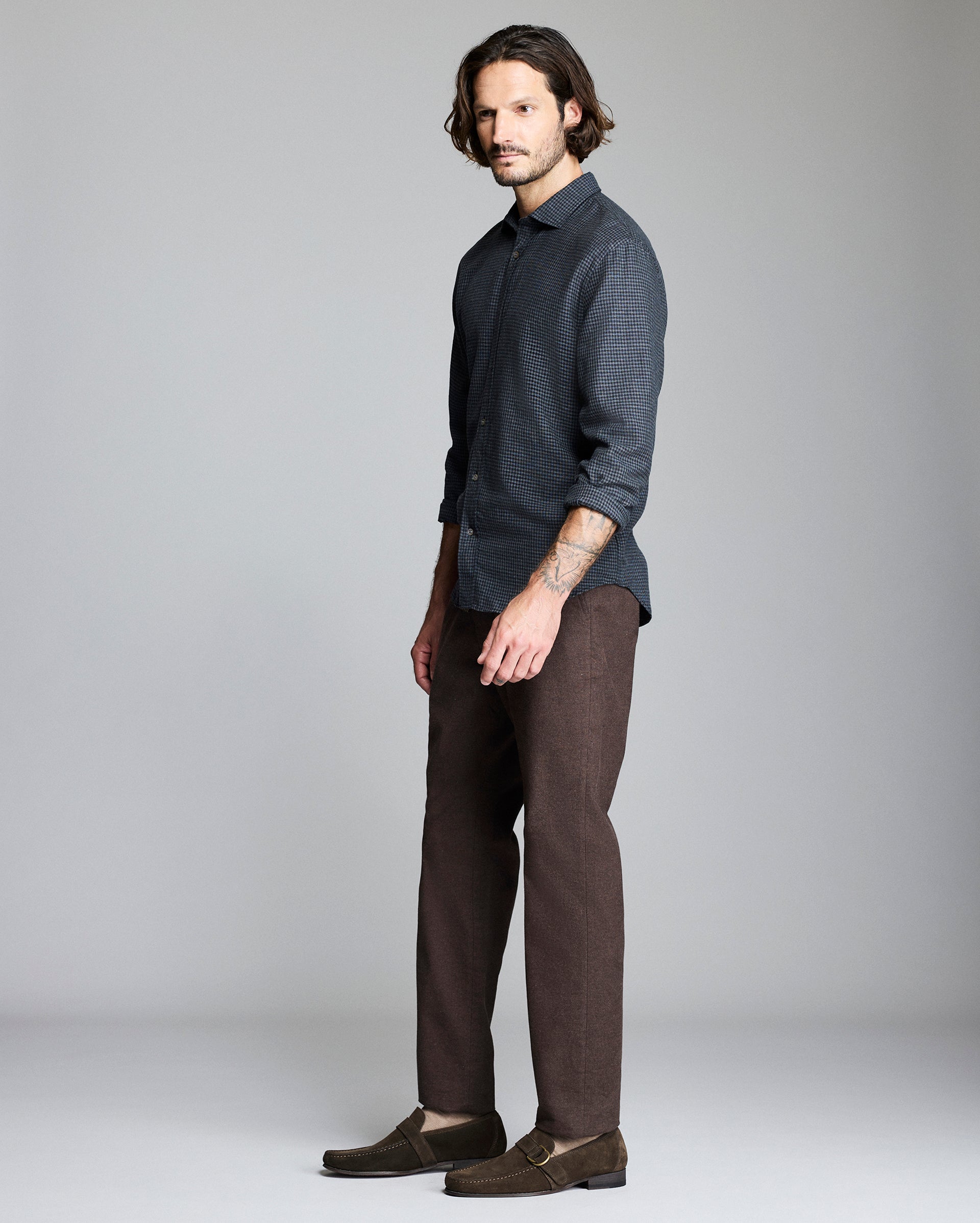 Man wearing a dark shirt and brown pants on a gray background