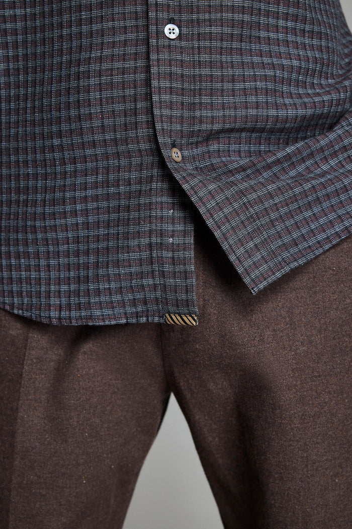 Close-up of a checkered shirt and brown pants on a plain background