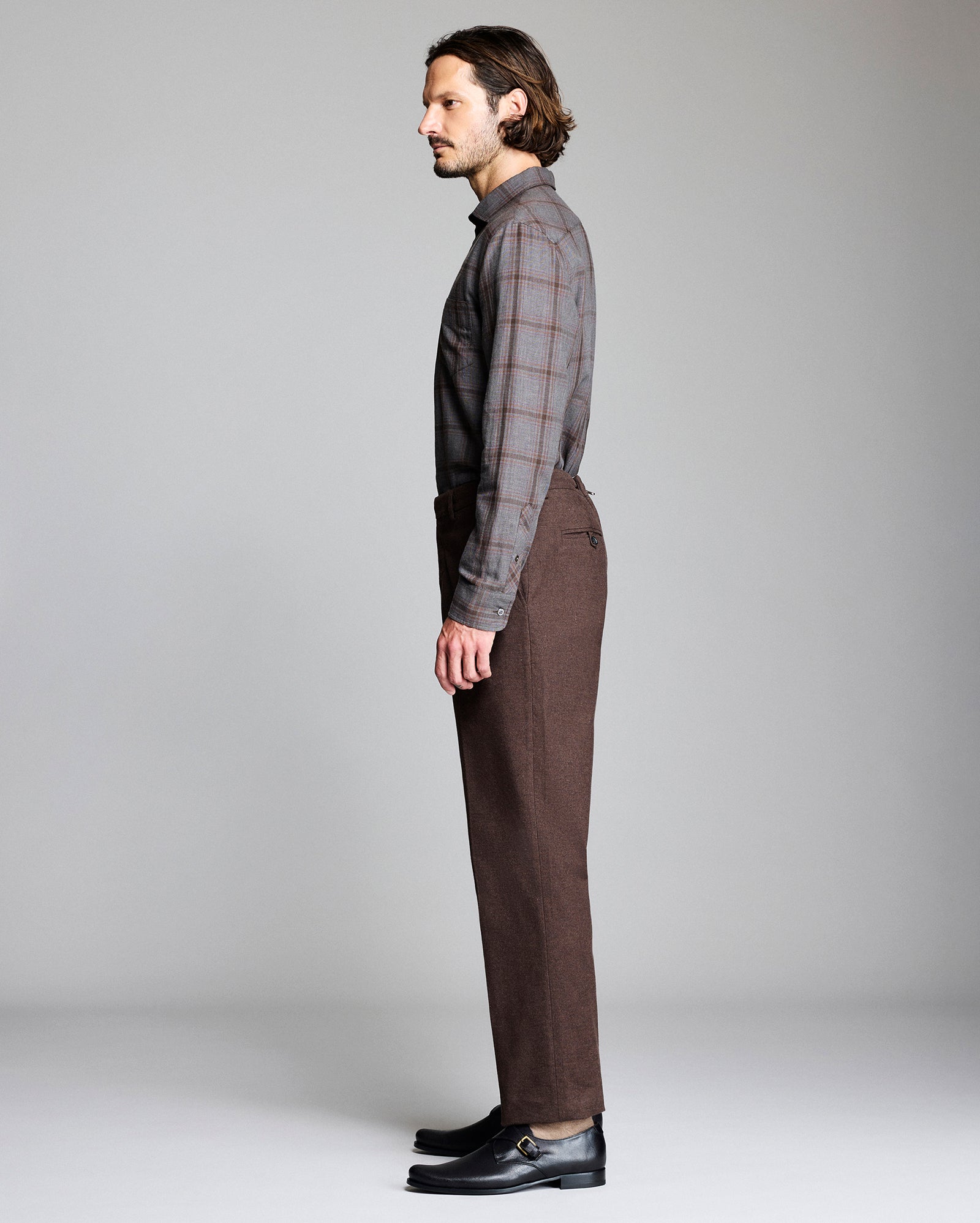 Man wearing a plaid shirt and brown pants on a plain background