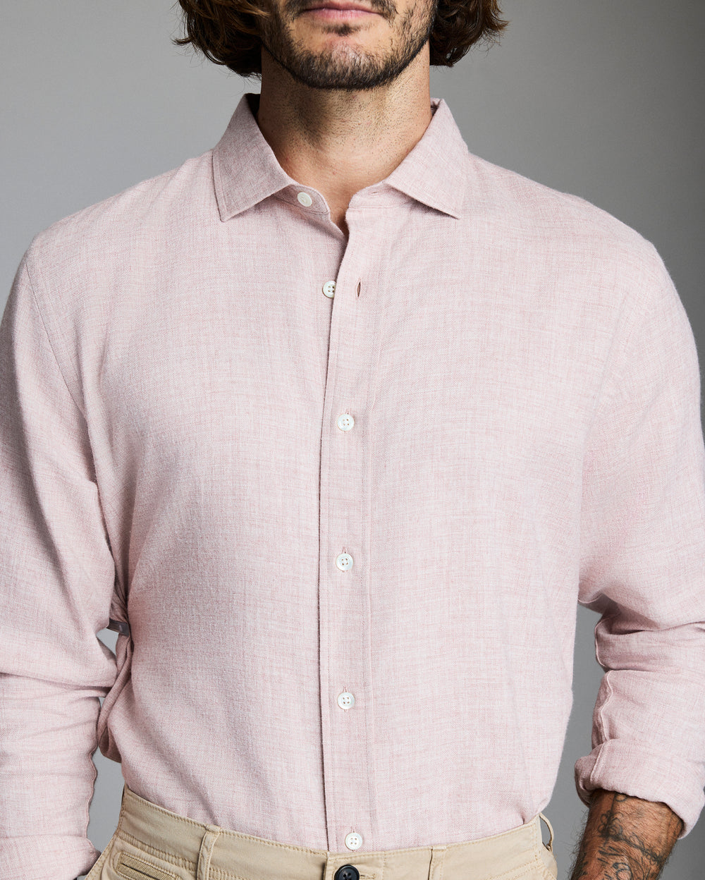 Man wearing a light pink shirt against a gray background