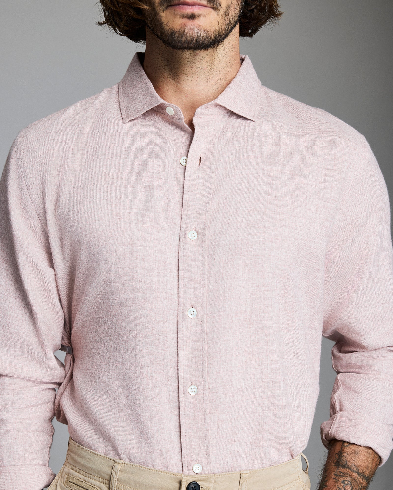 Man wearing a light pink shirt against a gray background