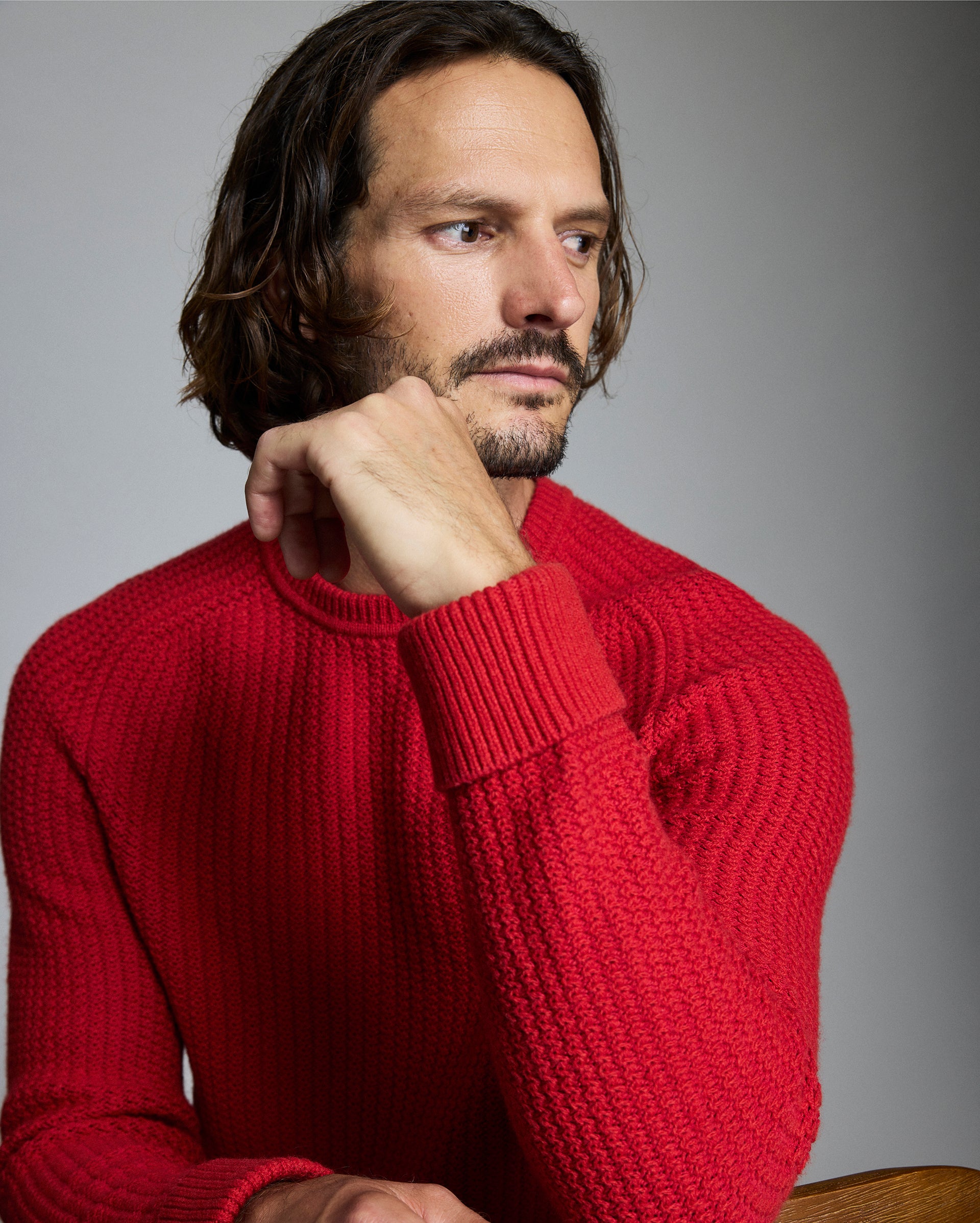 Man wearing a red sweater against a gray background