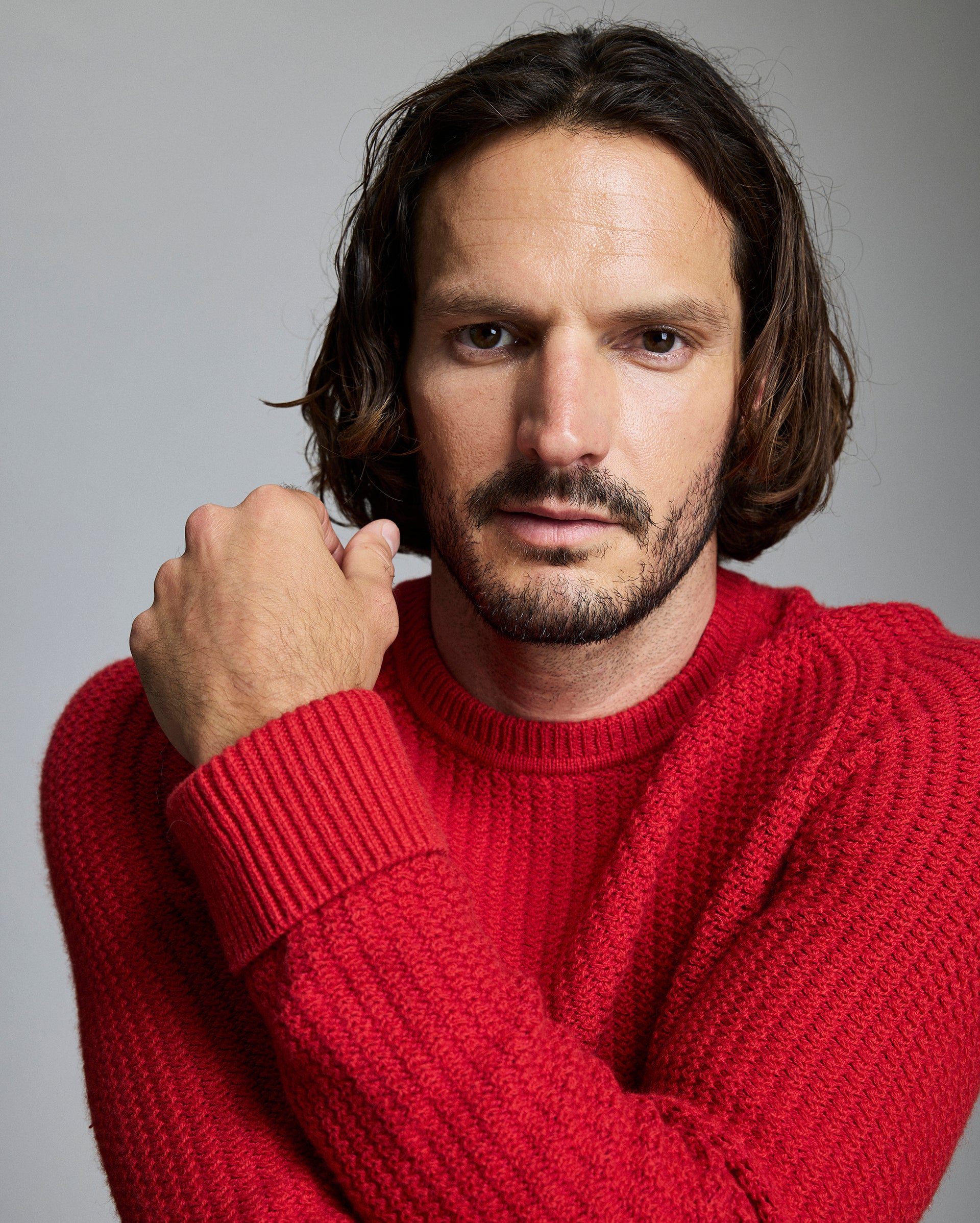 Man wearing a red sweater against a gray background