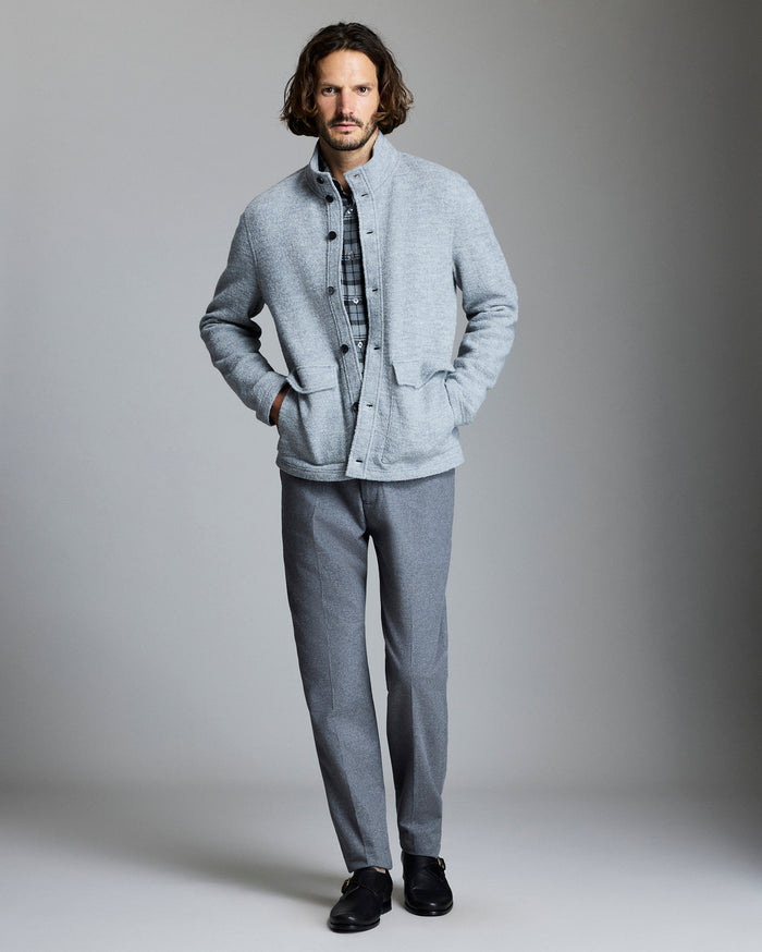 Man wearing a light gray jacket and pants against a plain background