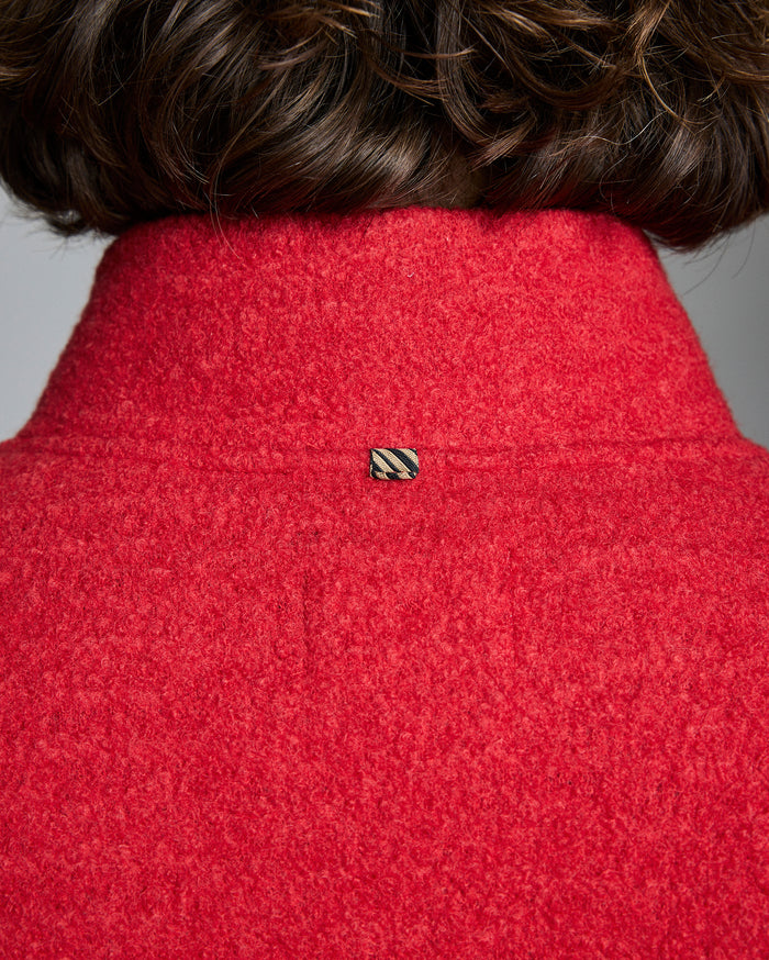 Close-up of a red textured garment with a brand logo on a gray background