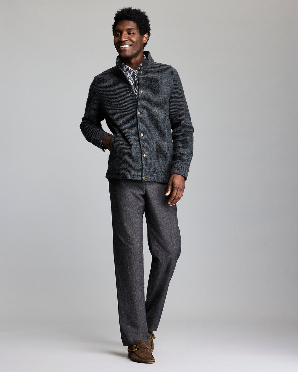 Man wearing a gray cardigan and pants on a plain background