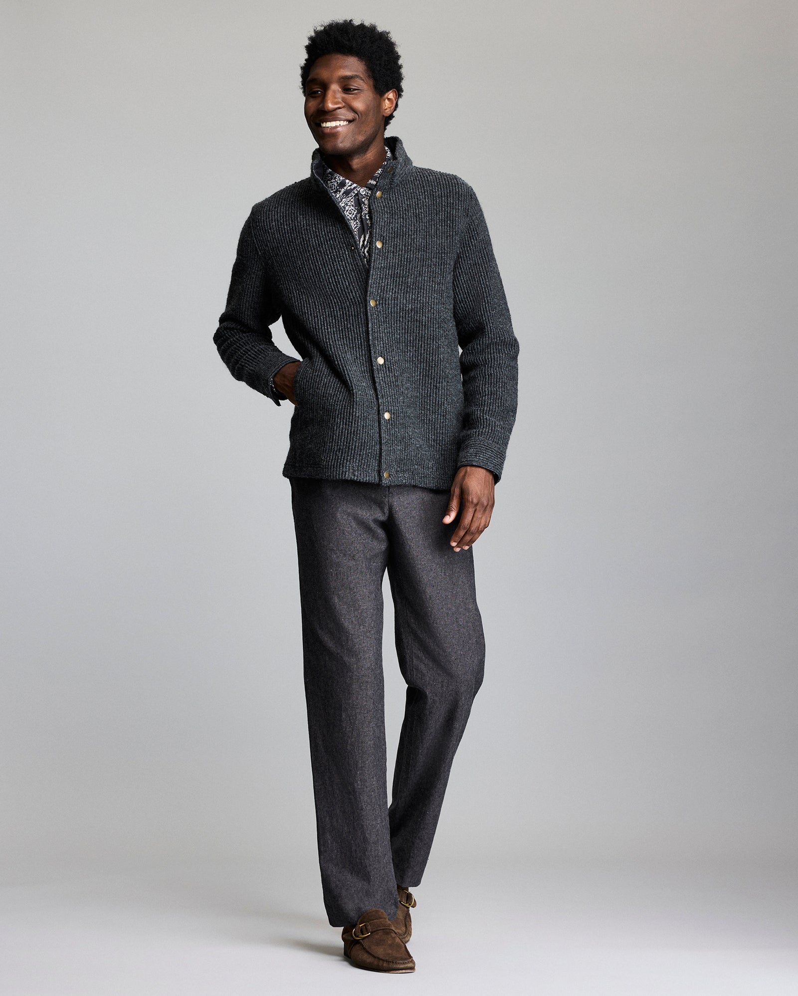 Man wearing a gray cardigan and pants on a plain background