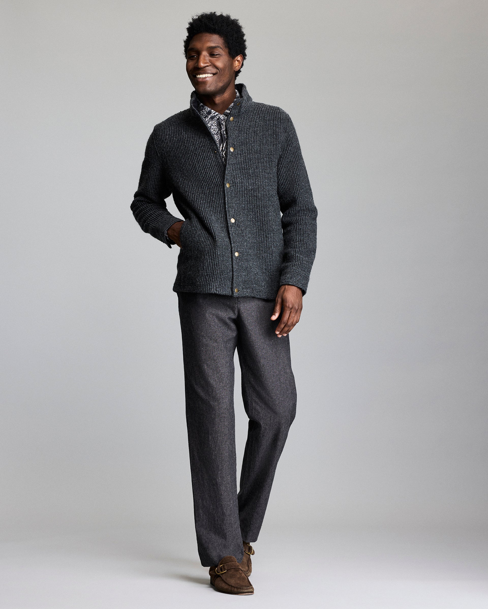 Man wearing a gray cardigan and pants on a plain background