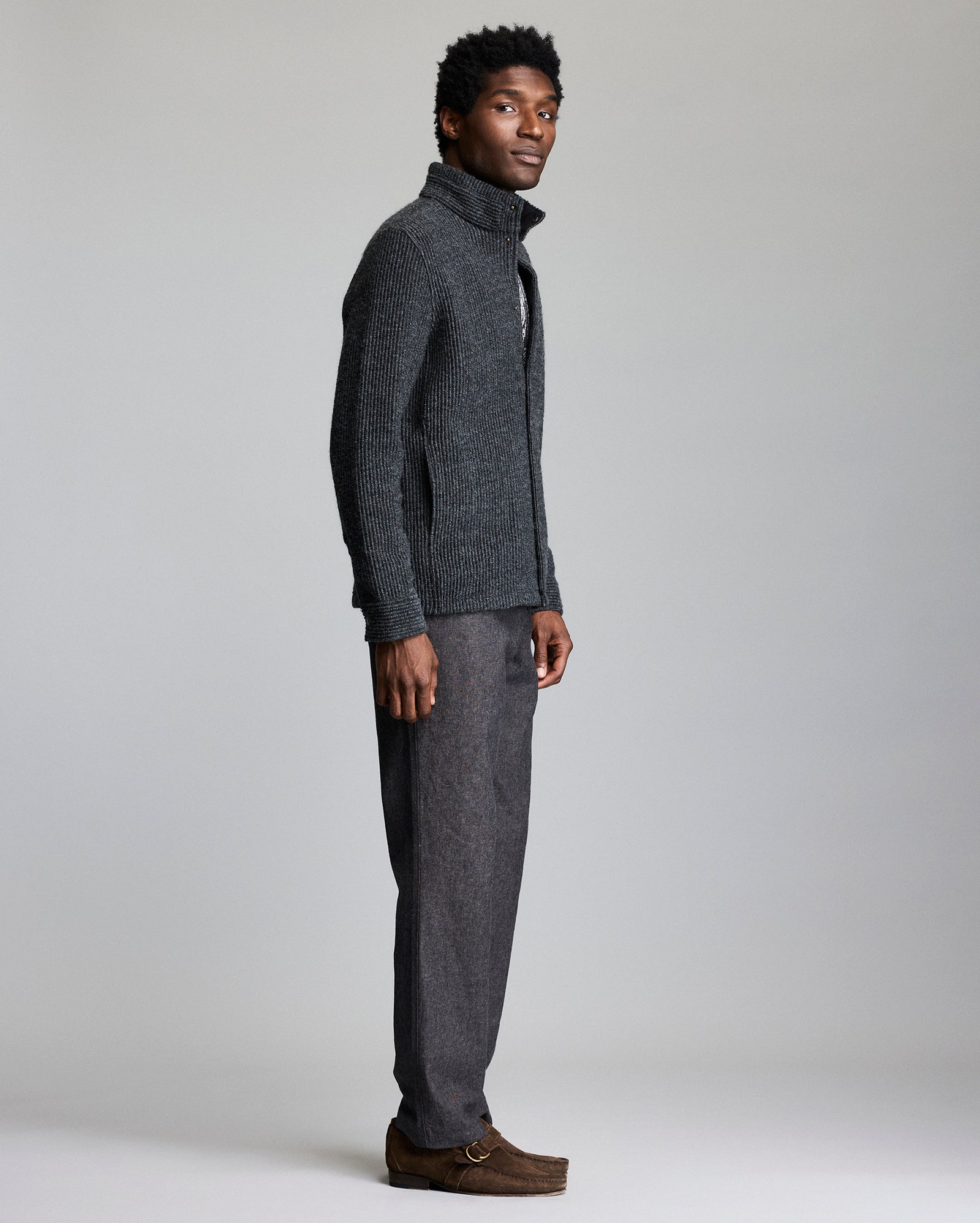 Man wearing a gray knit sweater and pants on a plain background