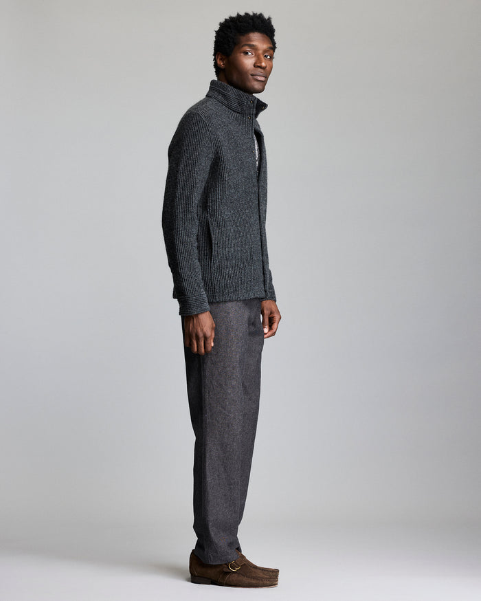 Man wearing a gray knit sweater and pants on a plain background