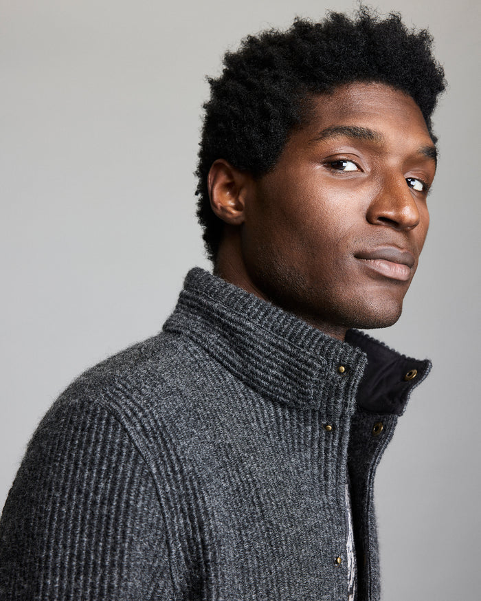 Man wearing a gray knitted jacket against a plain background