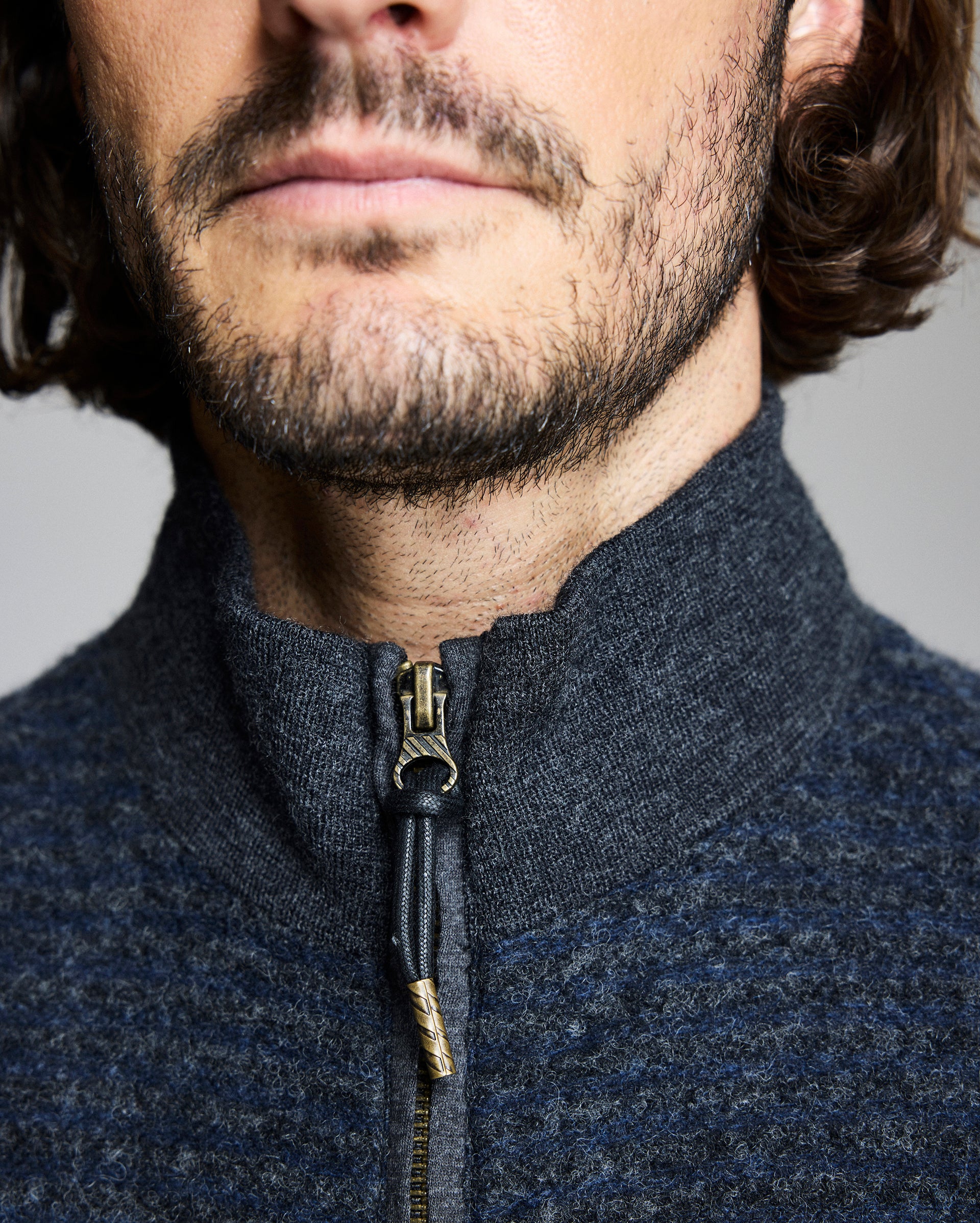 Close-up of a person wearing a dark blue zip-up garment with a neutral background