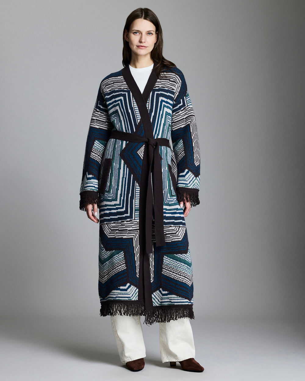 Woman wearing a long, patterned coat against a plain background