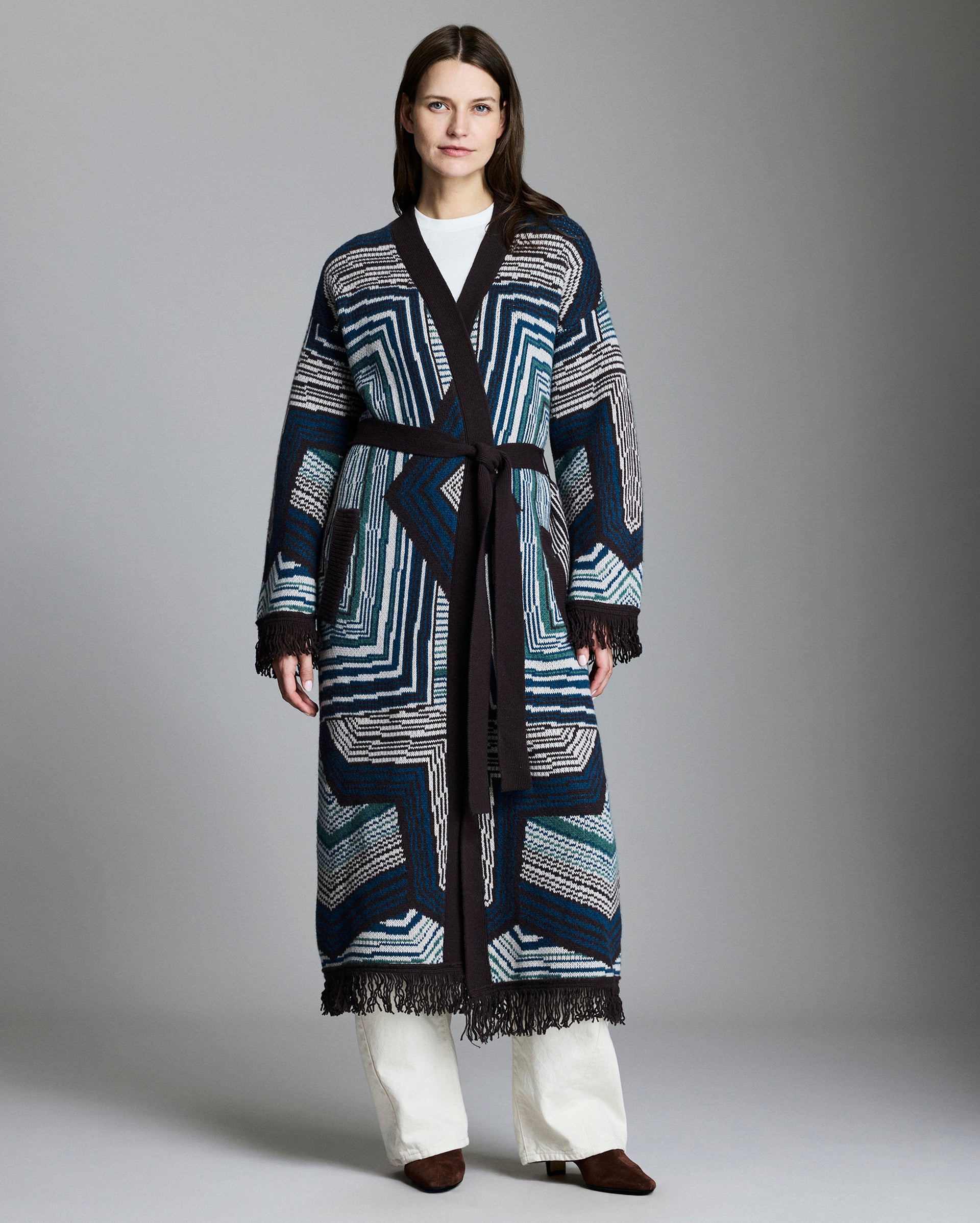 Woman wearing a long, patterned coat against a plain background