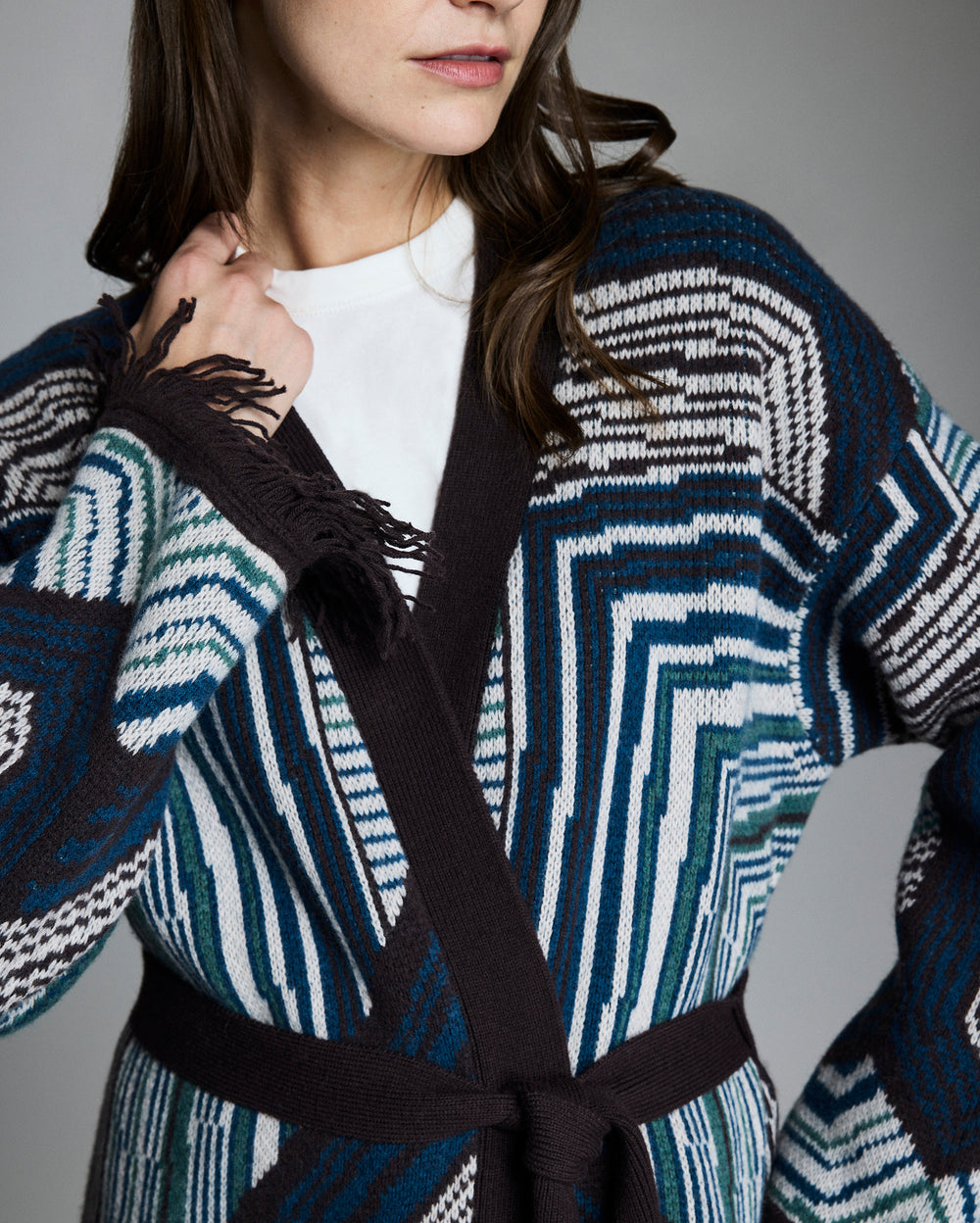 Person wearing a patterned cardigan with a gray background