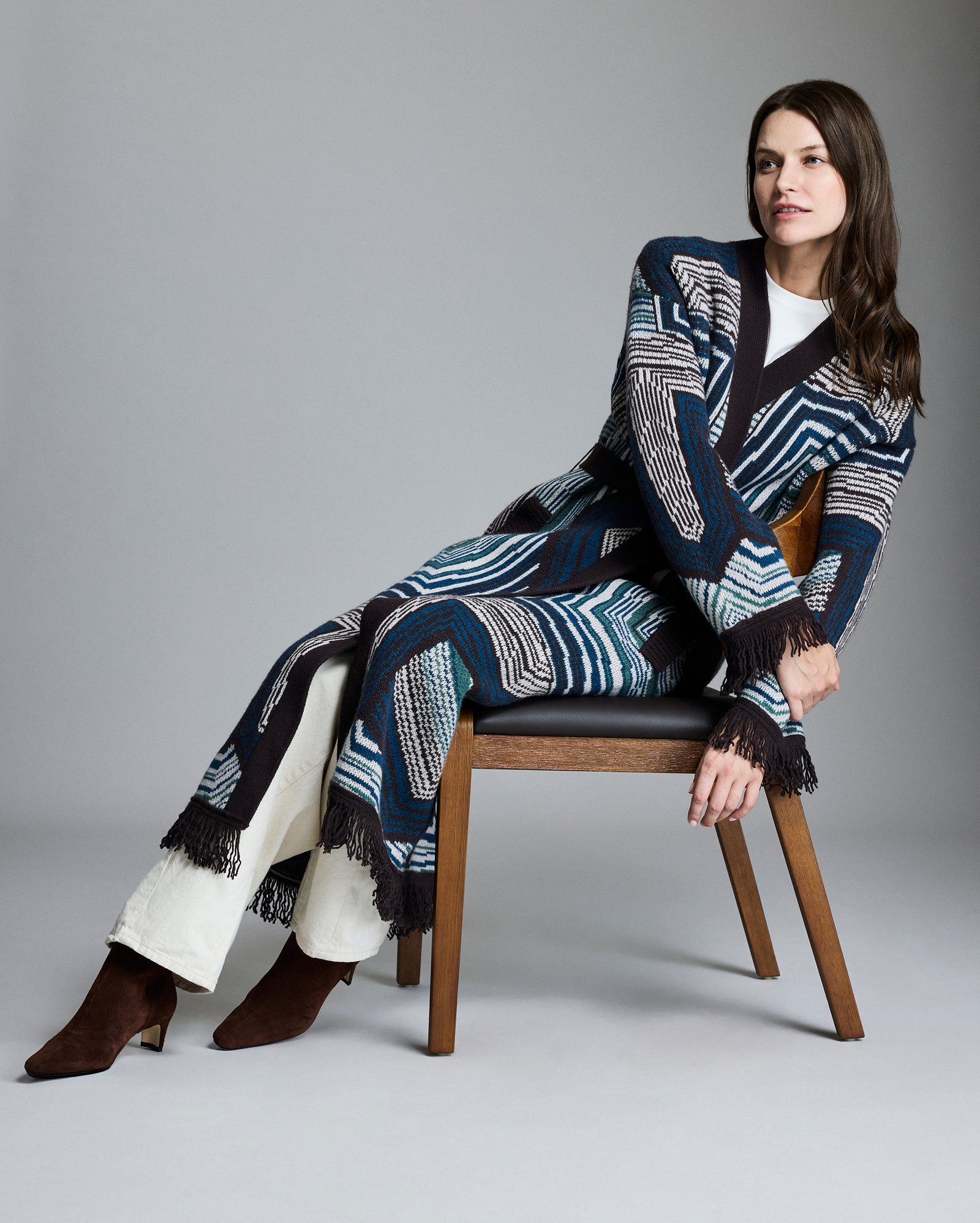 Woman sitting on a chair wearing a patterned outfit with a gray background