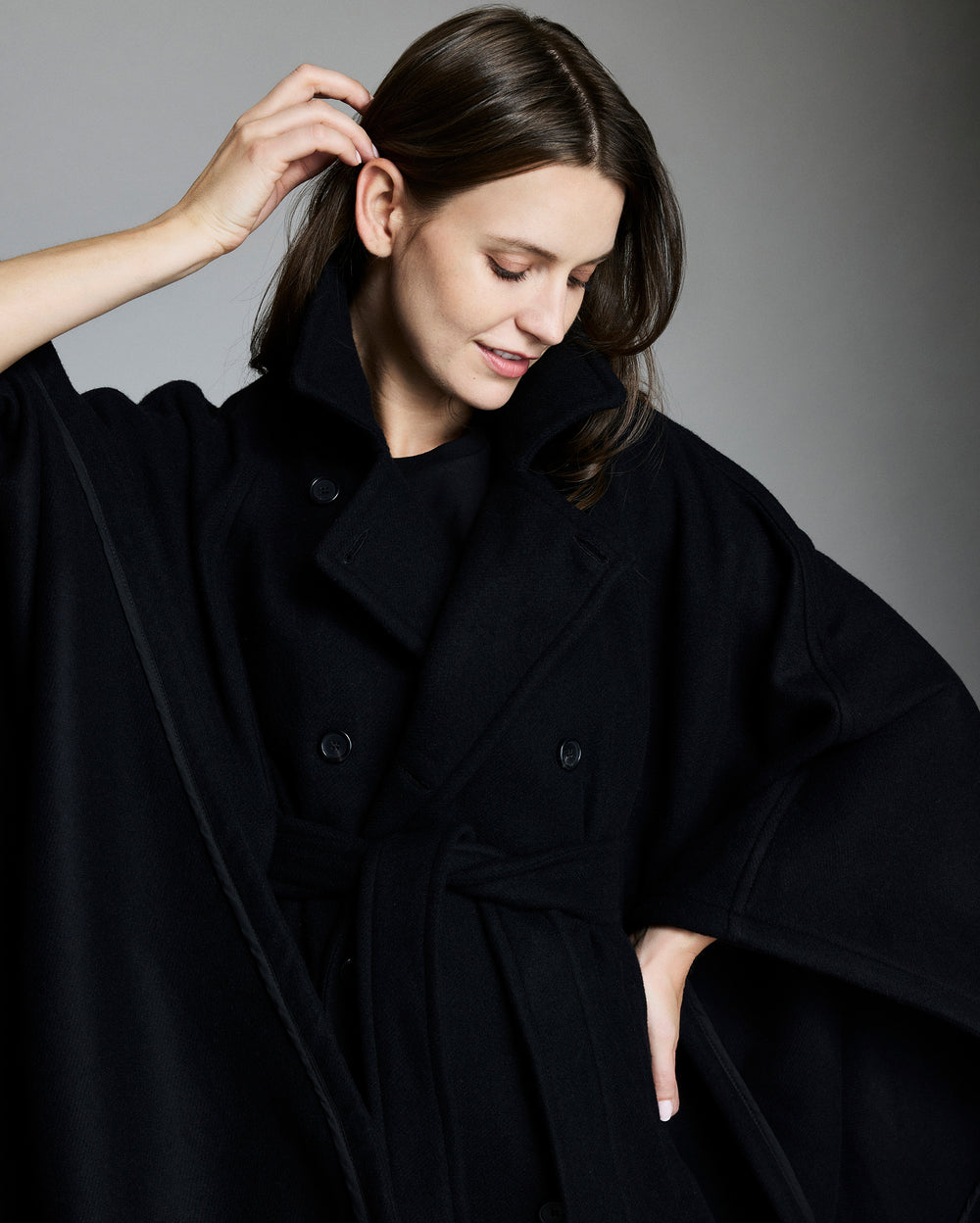 Woman wearing a black coat against a gray background