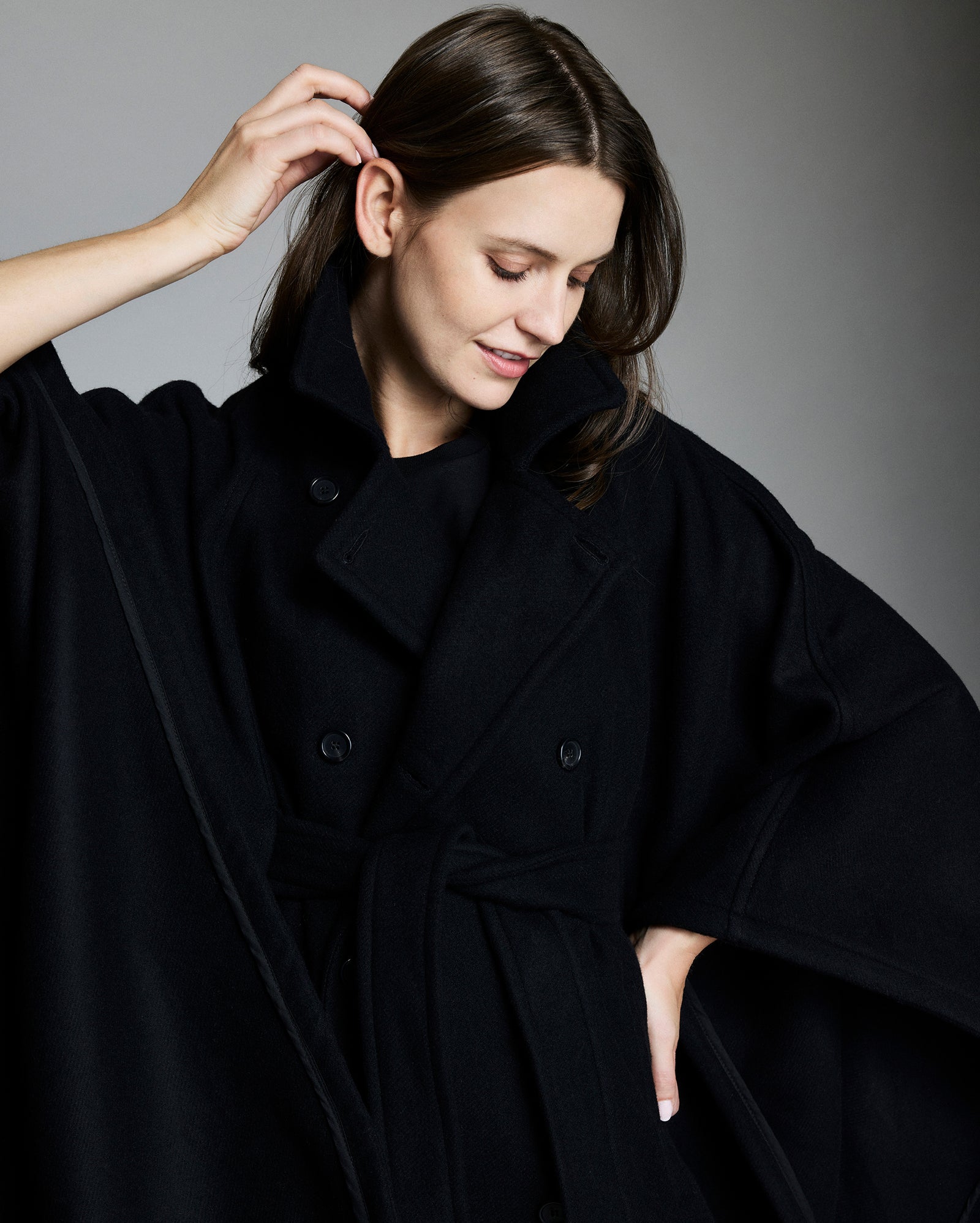 Woman wearing a black coat against a gray background