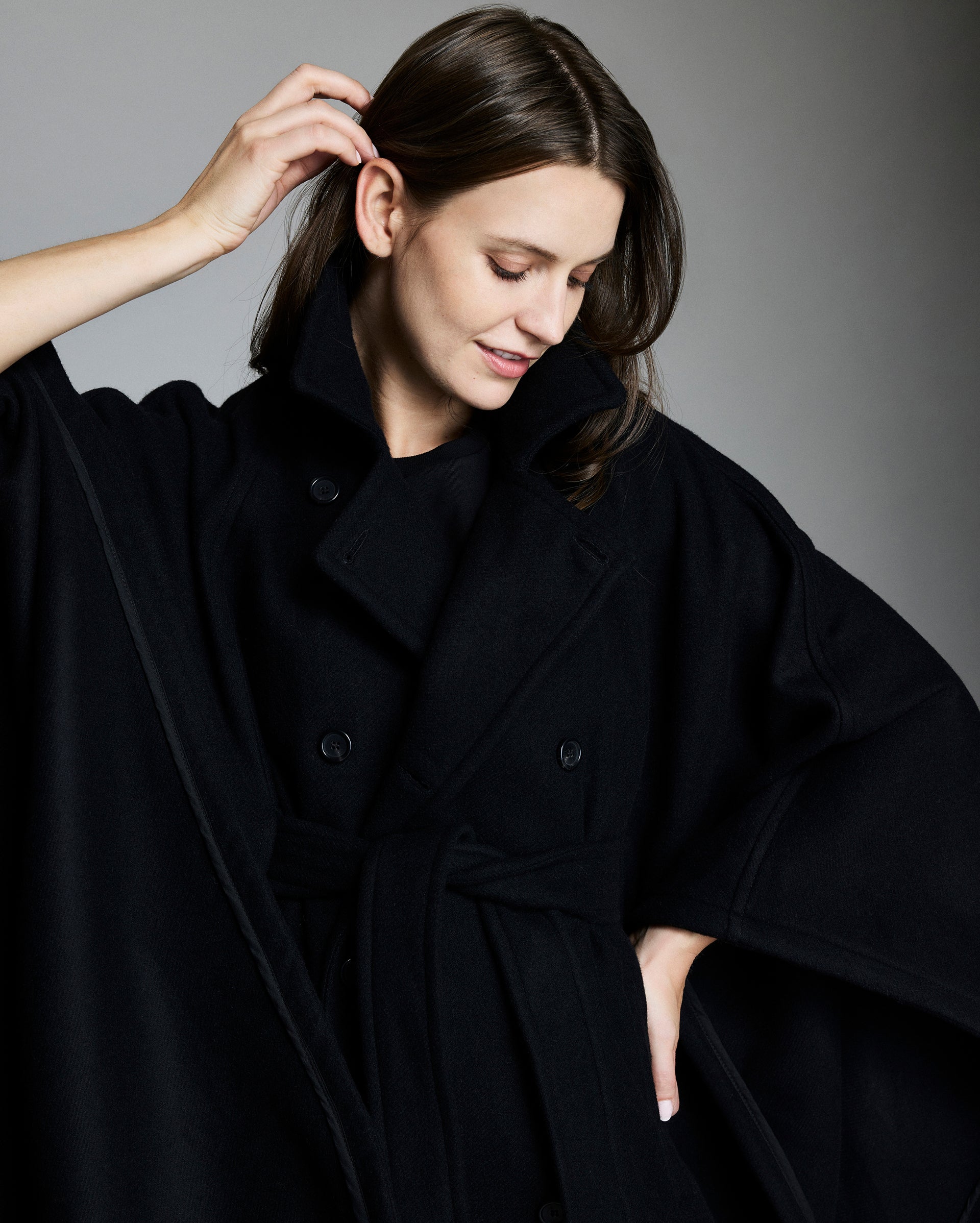 Woman wearing a black coat against a gray background