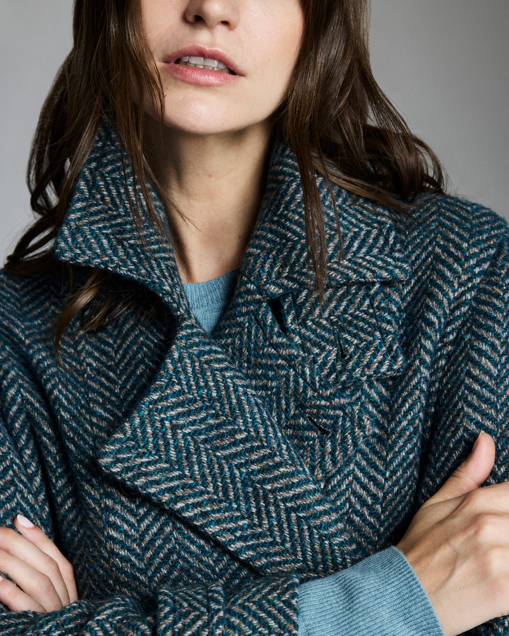 Person wearing a textured blue coat with a neutral background