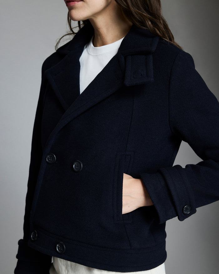 Navy peacoat worn by a person on a gray background