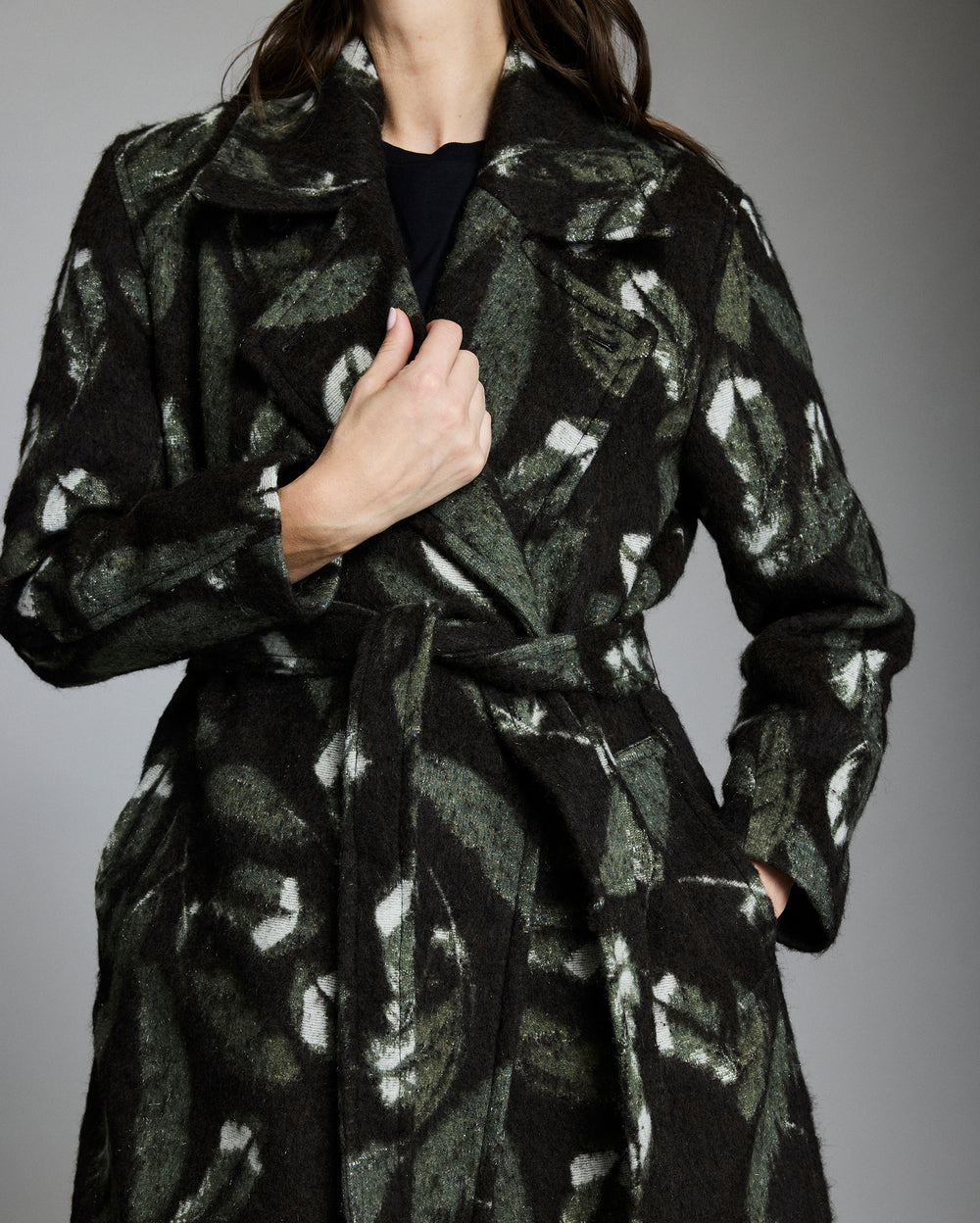 Black coat with abstract pattern worn by a person on a gray background