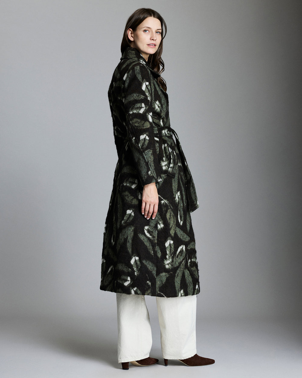 Woman wearing a black patterned coat against a gray background
