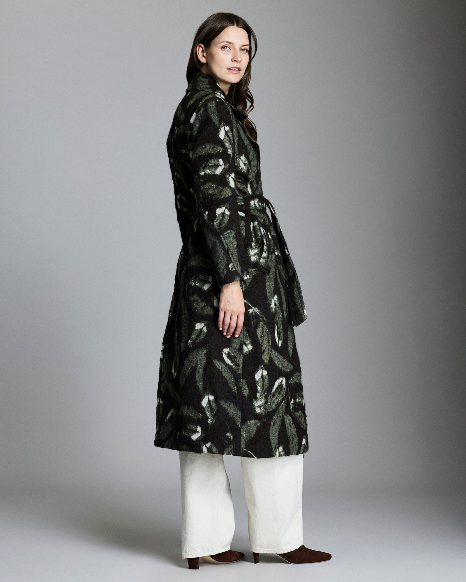 Woman wearing a black patterned coat against a gray background
