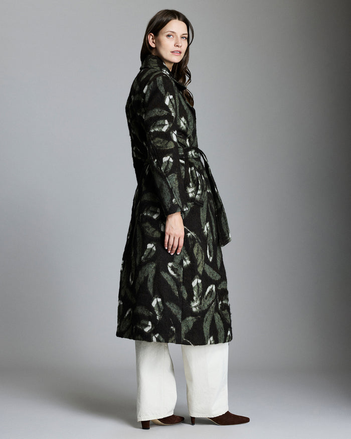 Woman wearing a black patterned coat against a gray background