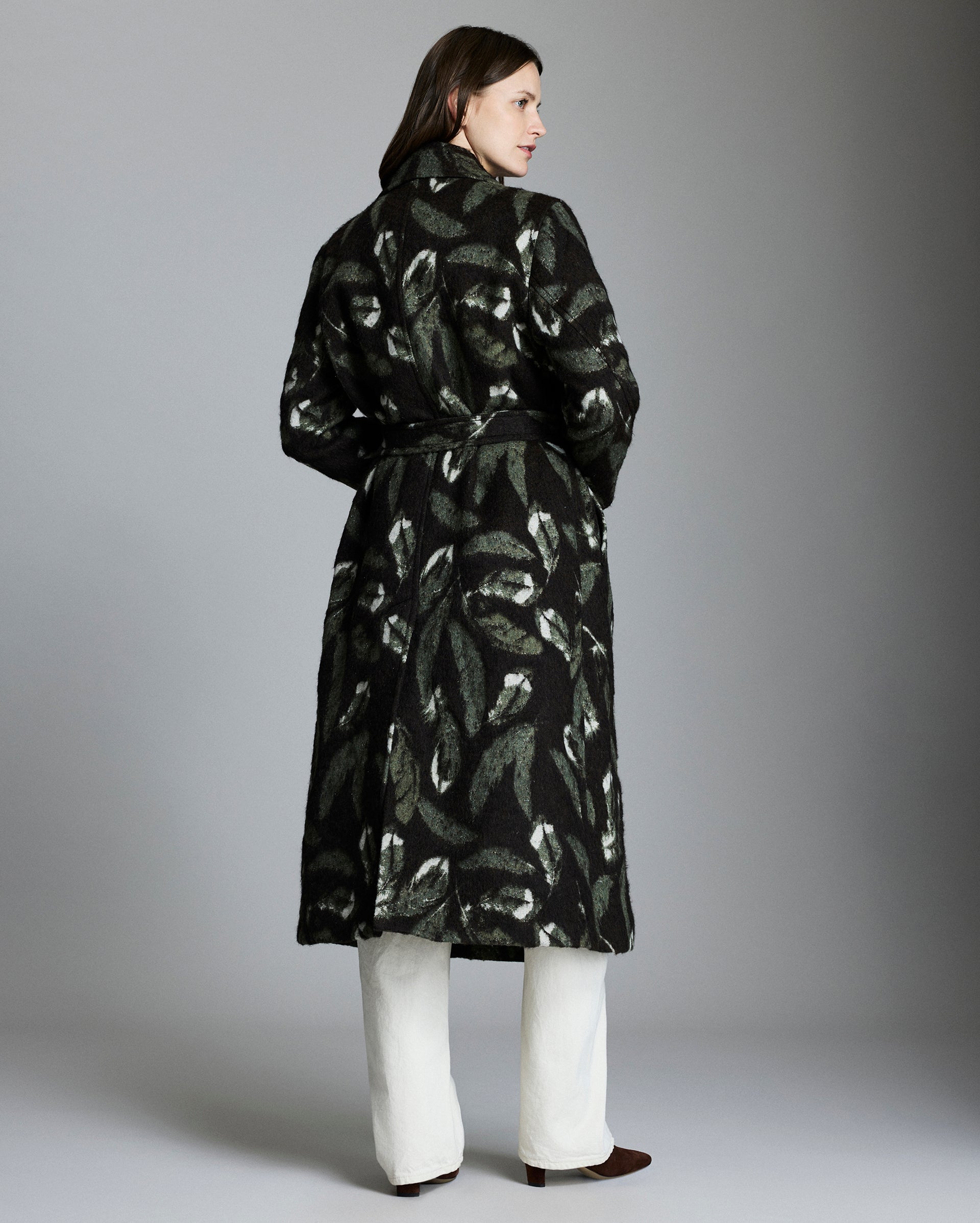 Woman wearing a black patterned coat against a gray background