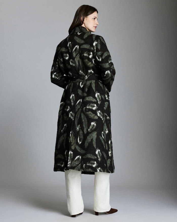 Woman wearing a black patterned coat against a gray background