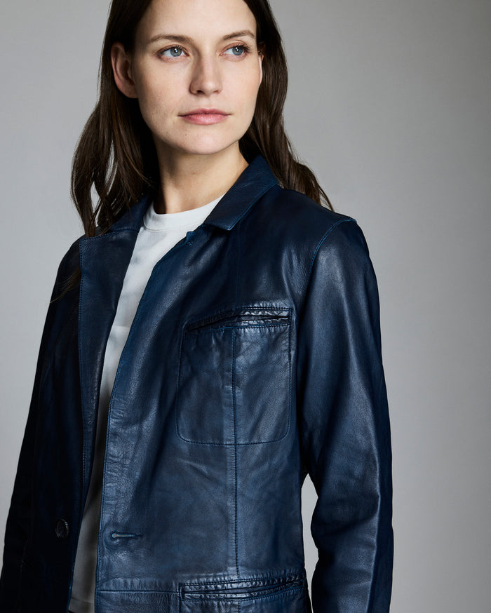 Woman wearing a dark blue leather jacket against a gray background