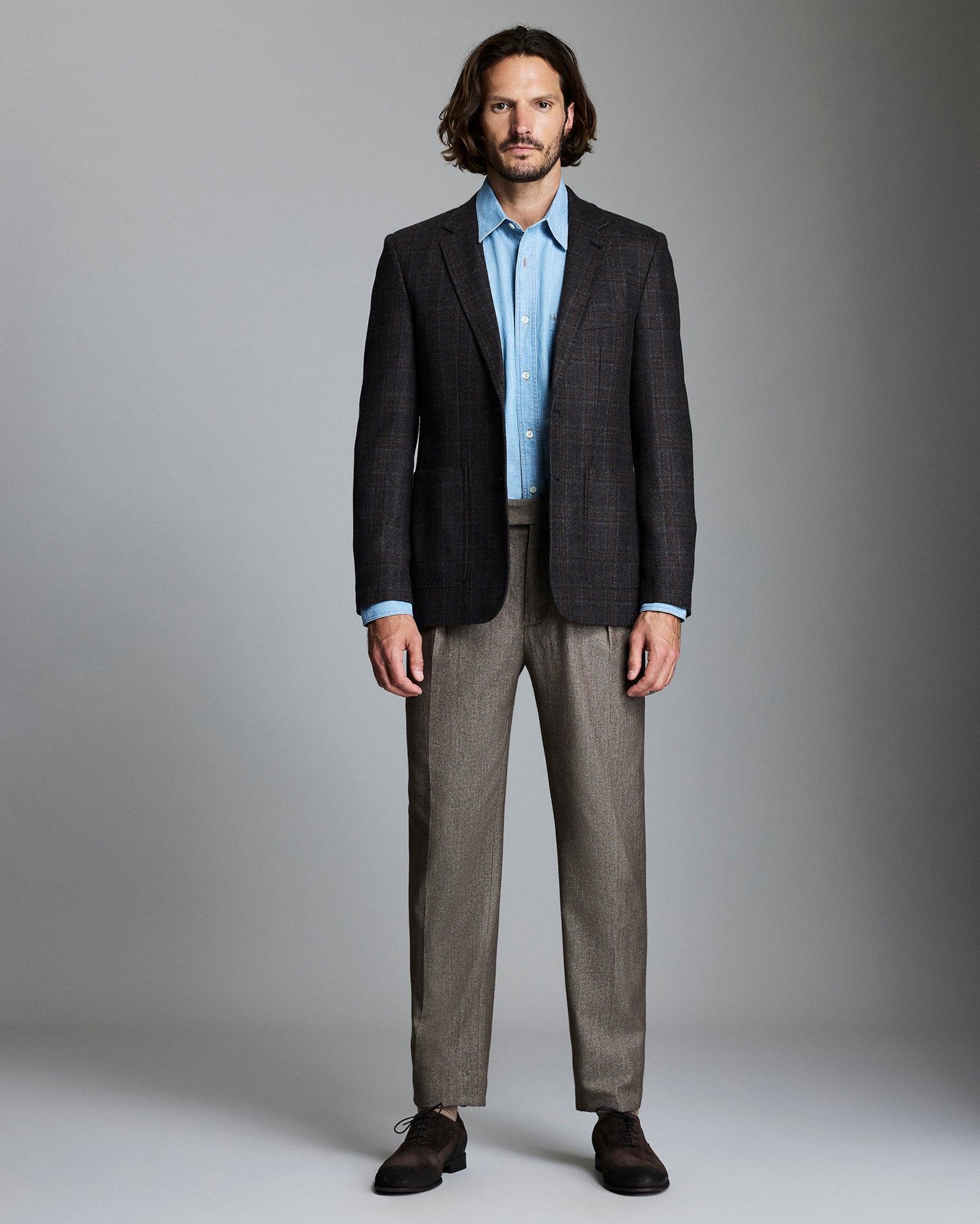 Man wearing a dark suit with a light shirt against a gray background