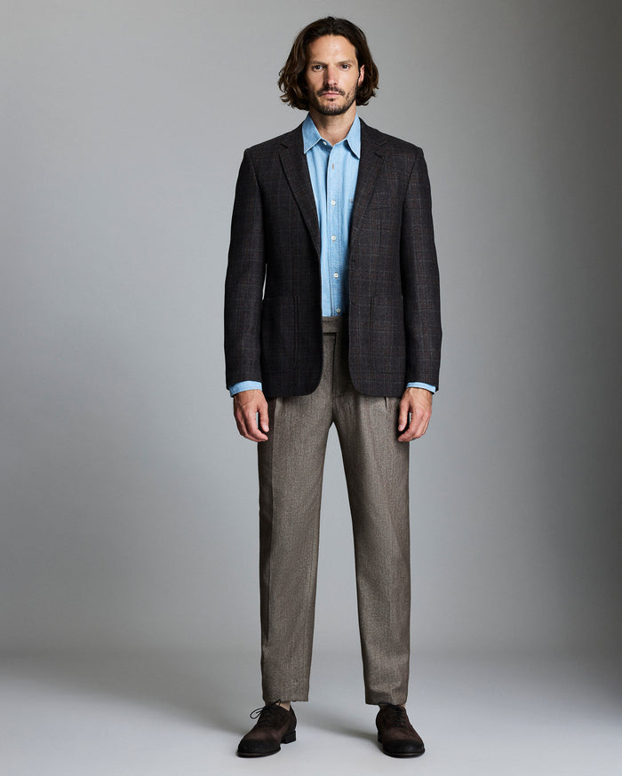 Man wearing a dark suit with a light shirt against a gray background