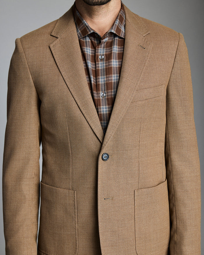 Brown blazer over a plaid shirt on a gray background