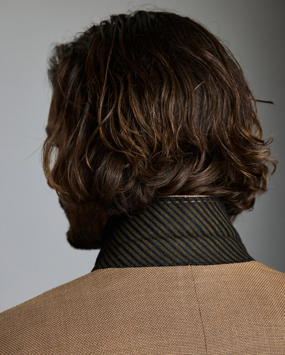 Man with wavy brown hair against a gray background
