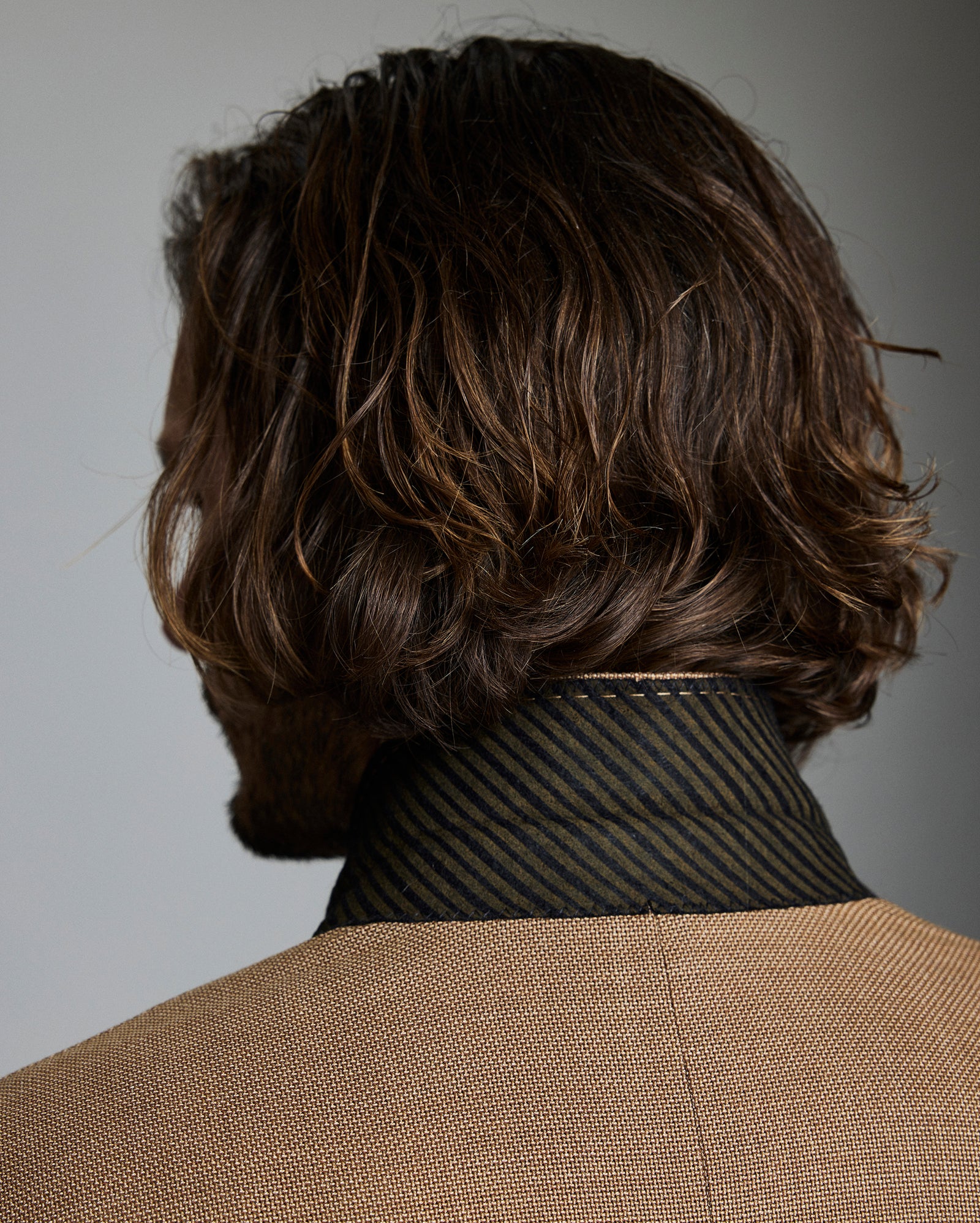 Man with wavy brown hair against a gray background