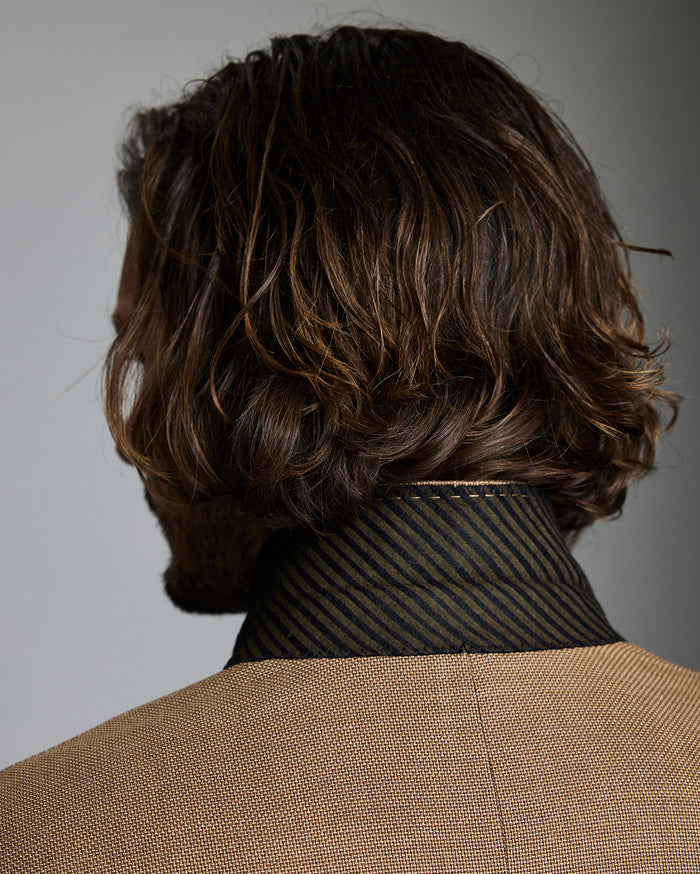 Man with wavy brown hair against a gray background